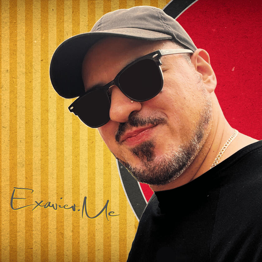 Close up image of Exavier Me wearing a cap forward and wearing sun glasses. A signature of Exavier's name is located in the lower left corner of the image.
